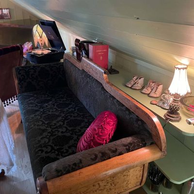 Gammel sleigh-benk med barnesko, grammofon og lamper på hyllen i loftsstuen